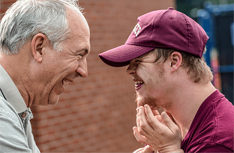 Two men talking to each other outside in a brick wall.